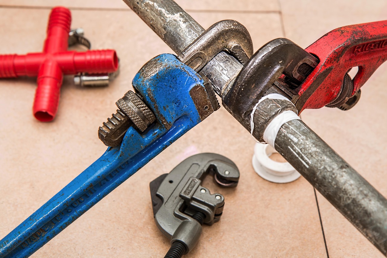 Plumbing wrenches and fittings laid out on drawings